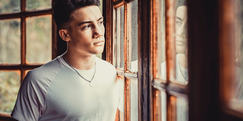 Young man looking out window